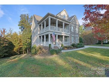 Charming two-story home boasting a double porch, stone accents, and a well-manicured lawn at 14010 Promenade Dr, Huntersville, NC 28078