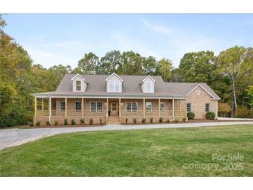 Charming brick home featuring a welcoming porch, dormer windows, and a beautifully landscaped front yard at 15906 Youngblood Rd, Charlotte, NC 28278