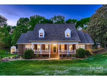Inviting brick home featuring a covered front porch, dormer windows, and lush green lawn at 308 Valhalla Dr, Harrisburg, NC 28075