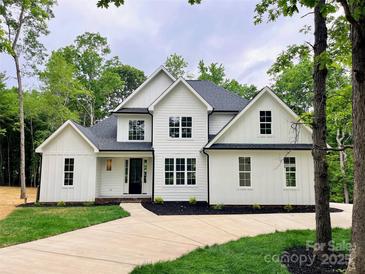 Stunning two-story home with white siding, black accents, a well manicured lawn, and a concrete driveway at 3308 Watkins Rd, Monroe, NC 28110