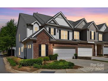 Charming townhome boasts a brick facade, attached garage, and professionally landscaped front yard at 5908 Glassport Ln, Charlotte, NC 28210