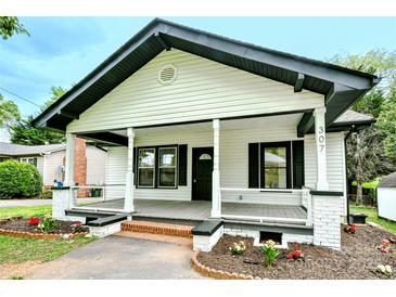 Charming single-story home featuring a welcoming front porch, black trim, and landscaped front yard at 307 E 2Nd St, Lowell, NC 28098