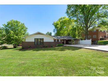 Charming brick home with a well-manicured lawn, covered carport, and lovely landscaping creating welcoming curb appeal at 319 Hatley Ne Cir, Concord, NC 28025