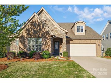 Charming brick and stone home with well-manicured lawn and a welcoming entrance, including an attached two-car garage at 9565 Horsebit Ln, Concord, NC 28027