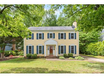 Charming yellow two-story home with blue shutters, lush front lawn, and mature shade trees at 1007 Doby Springs Dr, Charlotte, NC 28262
