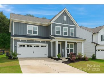 Charming two-story home with grey siding, white trim, attached garage, and manicured landscaping at 1390 Cedardale Ln, Denver, NC 28037