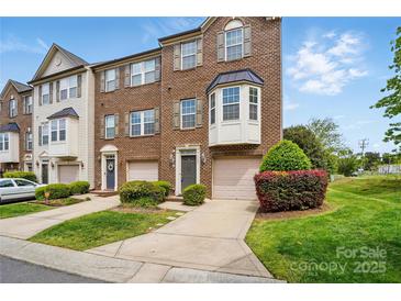 Beautiful three-story brick townhome with a manicured lawn and attached garage at 7753 Jackson Pond Dr, Charlotte, NC 28273