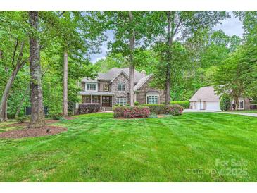 Charming home with stone and brick exterior, manicured lawn, mature trees and lush landscaping at 14131 Lea Point Ct, Huntersville, NC 28078