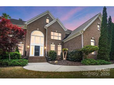 Brick home featuring an arched entryway, manicured landscaping and inviting front steps at 16532 Flintrock Falls Ln, Charlotte, NC 28278