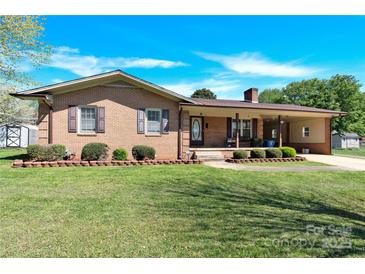 Charming brick home with a well-maintained lawn, mature landscaping, and an inviting covered front porch at 2116 1St Avenue Nw Pl, Hickory, NC 28601
