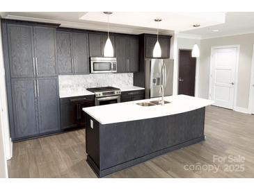 Modern kitchen featuring stainless steel appliances, island with white countertops and dark wood cabinets at 222 S Caldwell St # 1801, Charlotte, NC 28202