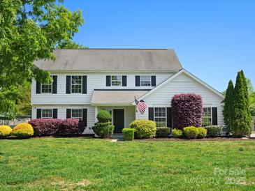 Charming two-story home featuring a well-manicured lawn, mature trees, and a welcoming facade at 3002 Fair Meadows Dr, Monroe, NC 28110