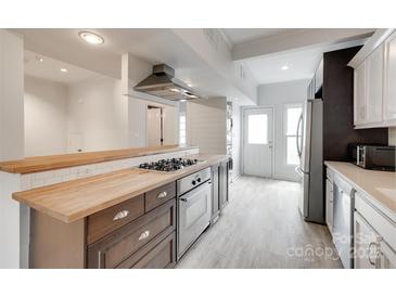 Modern kitchen with wood counters, stainless steel appliances, and updated gray wood-look floors at 5901 Quail Hollow Rd # G, Charlotte, NC 28210