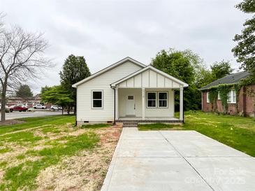 Charming single-story home with white siding, a cozy front porch, and a concrete driveway at 712 N Washington St, Shelby, NC 28150
