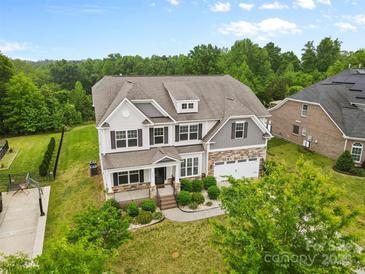 Traditional two story home showcasing a landscaped yard, covered porch, and neutral color palette at 9303 Raven Top Dr, Mint Hill, NC 28227