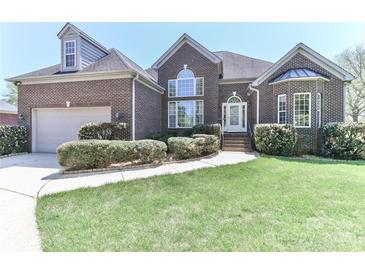 Charming brick home features a manicured lawn, lush bushes, and an attached two-car garage at 115 Players Park Cir, Statesville, NC 28677