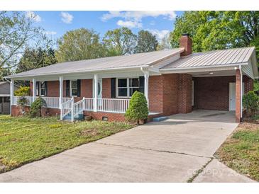 Charming single-story red brick home featuring a metal roof, a front porch, and a long concrete driveway at 1195 Ralph B Keener Rd, Lincolnton, NC 28092