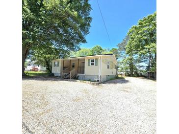 Inviting one-story home with a covered porch and gravel driveway, nestled among mature trees at 1307 Washington Ln, Kannapolis, NC 28083
