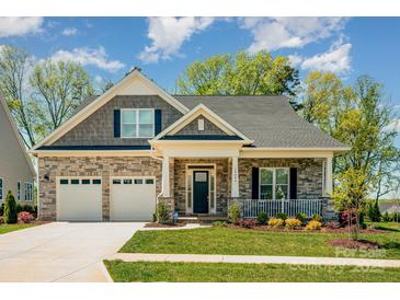 Charming home featuring a stone facade, two-car garage, covered porch, and beautifully landscaped front yard at 19006 Brandon James Dr, Cornelius, NC 28031