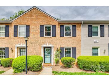 Charming brick townhouse with navy shutters, tidy landscaping and a pop of color from the front door at 4607 Hedgemore Dr # H, Charlotte, NC 28209