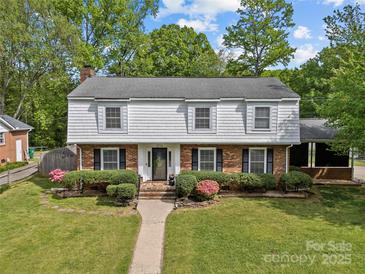 Classic two-story home features a landscaped front yard, brick and shingle facade, and inviting walkway to the front door at 6035 Idlebrook Dr, Charlotte, NC 28212