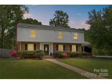 Two-story home boasts a well-maintained front yard, brick facade, complemented by symmetrical shrubbery and a paved walkway at 6035 Idlebrook Dr, Charlotte, NC 28212