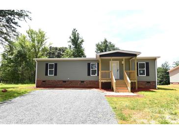 Charming single-story home features a covered porch, gravel driveway and tidy landscaping at 828 Long Bow Rd, Salisbury, NC 28144