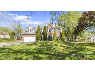 Inviting two-story brick home featuring a lush green lawn and beautiful landscaping with mature trees at 111 Woodfern Pl, Mooresville, NC 28115