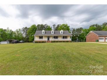 Inviting yellow house with a charming front porch and a large, well-maintained front yard at 1990 Country Club Dr, Lancaster, SC 29720