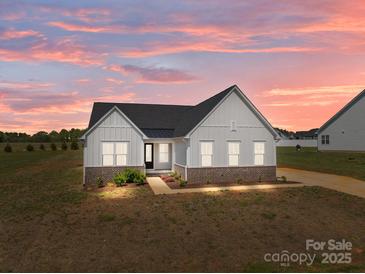 Charming exterior of a single-story home with white siding, black roof, and manicured front yard at sunset at 210 Goldenrod Cir, Salisbury, NC 28147
