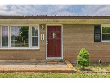Home's front door featuring brick facade, manicured lawn and decorative tree at 7527 Old Shelby Rd, Vale, NC 28168