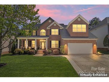 Charming brick home featuring a well-manicured lawn, covered porch, and two-car garage, captured at twilight at 9715 Aragorn Nw Ln, Charlotte, NC 28269