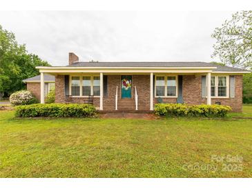 Charming brick home with covered front porch and inviting teal door with colorful wreath at 1162 E Doc Garris Rd, Lancaster, SC 29720