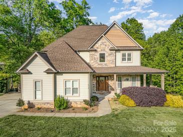 Charming two-story home features a stone and siding exterior, complemented by a covered front porch and landscaped yard at 1713 Mt Isle Harbor Dr, Charlotte, NC 28214