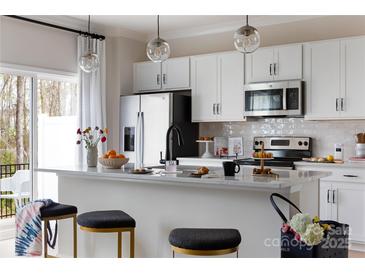 Modern kitchen featuring white cabinets, stainless steel appliances, and a breakfast bar with pendant lighting at 2021 Endeavor Run, Charlotte, NC 28269