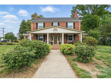 Charming brick two-story home with inviting front porch, columns, and mature landscaping at 901 Central Dr, Kannapolis, NC 28083