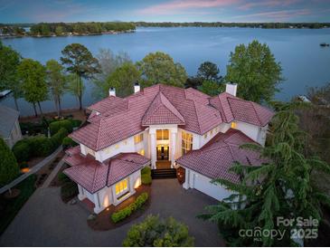 Expansive lakefront home features a red tile roof, manicured landscaping, and a circular driveway at 102 Eastham Ct, Mooresville, NC 28117