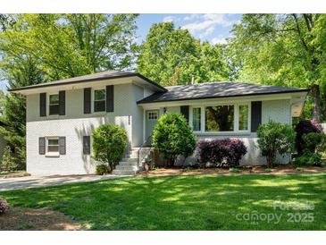 Charming two-story home with a painted brick facade, manicured landscaping and black window shutters at 1043 Nancy Dr, Charlotte, NC 28211