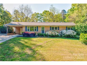 Charming brick home featuring blue shutters and colorful landscaping in the front yard at 113 Princess Ln, Dallas, NC 28034