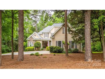 Traditional home with tan siding and stone accents nestled among lush trees and landscaping at 19729 Callaway Hills Ln, Davidson, NC 28036