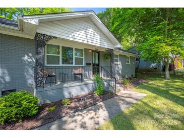 Charming gray-brick home featuring a cozy front porch with decorative metal railings and outdoor seating at 2601 Dora Dr, Charlotte, NC 28215