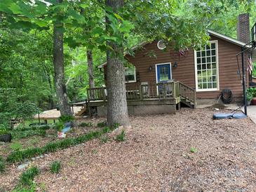 Charming brown home with a blue door, large window, and wooden deck nestled among mature trees at 33611 Mann Rd, Albemarle, NC 28001
