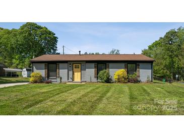 Charming home featuring a well manicured lawn, a yellow front door, and lovely landscaping at 500 Dedmon Dr, Charlotte, NC 28216
