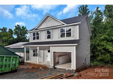 Two-story home featuring gray siding, black roof, open garage, and charming curb appeal against a blue sky backdrop at 530 Gantt St, Mooresville, NC 28115