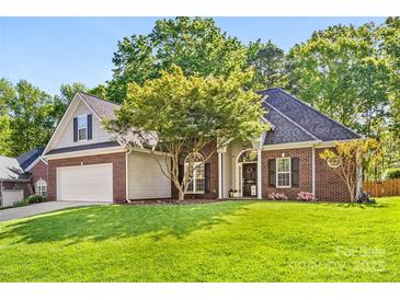 Charming brick home featuring a well-manicured lawn and beautiful landscaping at 6002 Sentinel Dr, Indian Trail, NC 28079