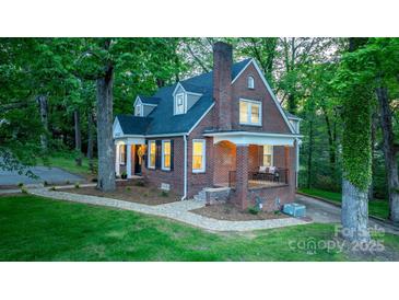 Charming brick home featuring manicured lawn, covered porch, and mature trees, perfect for serene living at 625 4Th Street Nw Dr, Hickory, NC 28601
