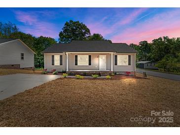 Charming single-story home featuring a well-manicured lawn and inviting front porch, perfect for relaxing evenings at 104 Cleveland Ave, Albemarle, NC 28001