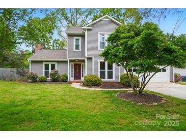 Charming two-story home featuring gray siding, a well-manicured lawn, mature trees, and a delightful, vibrant purple front door at 3908 Brittany Ct, Indian Trail, NC 28079