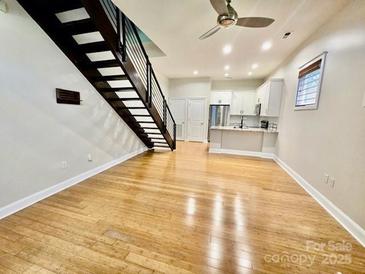 Bright living room features hardwood floors, stairs, a ceiling fan and open access to the modern kitchen at 627 N Alexander St, Charlotte, NC 28202
