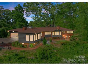 Stunning elevated home with a brick facade, modern gray siding, and large windows surrounded by lush greenery at 916 E Park Dr, Lincolnton, NC 28092